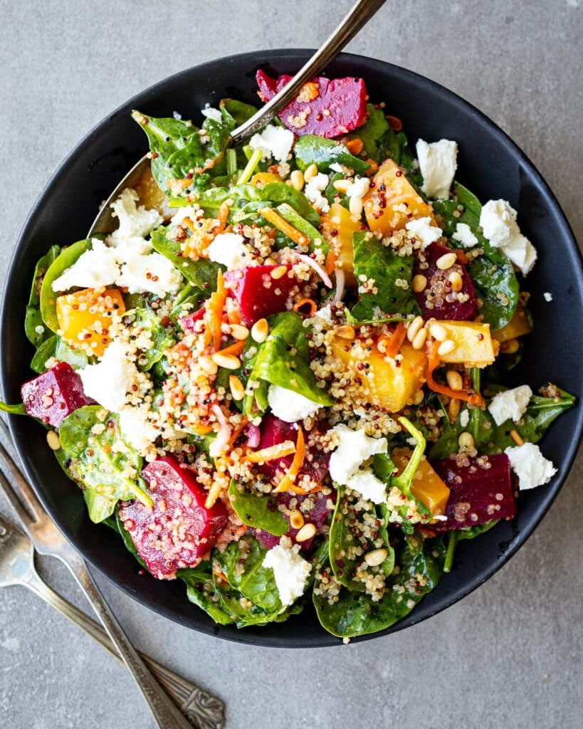 Beet and quinoa salad in a black bowl with vintage forks on the side. 