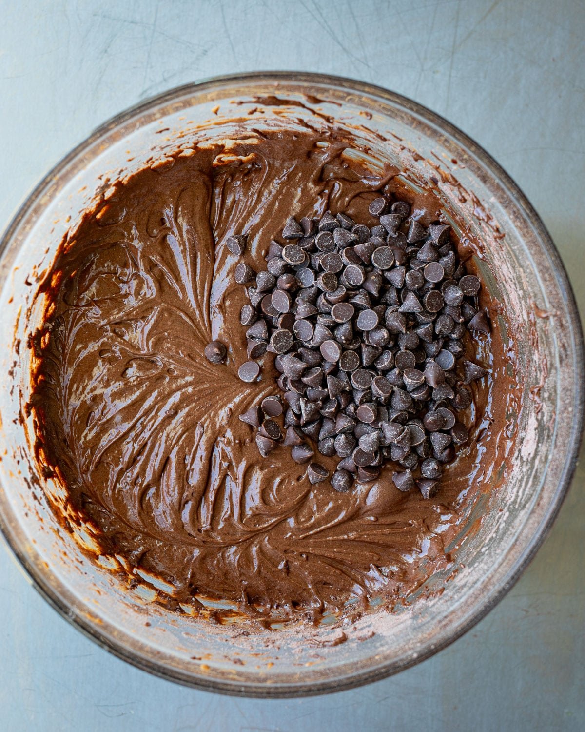 Brownie batter with chocolate chips in a glass bowl.