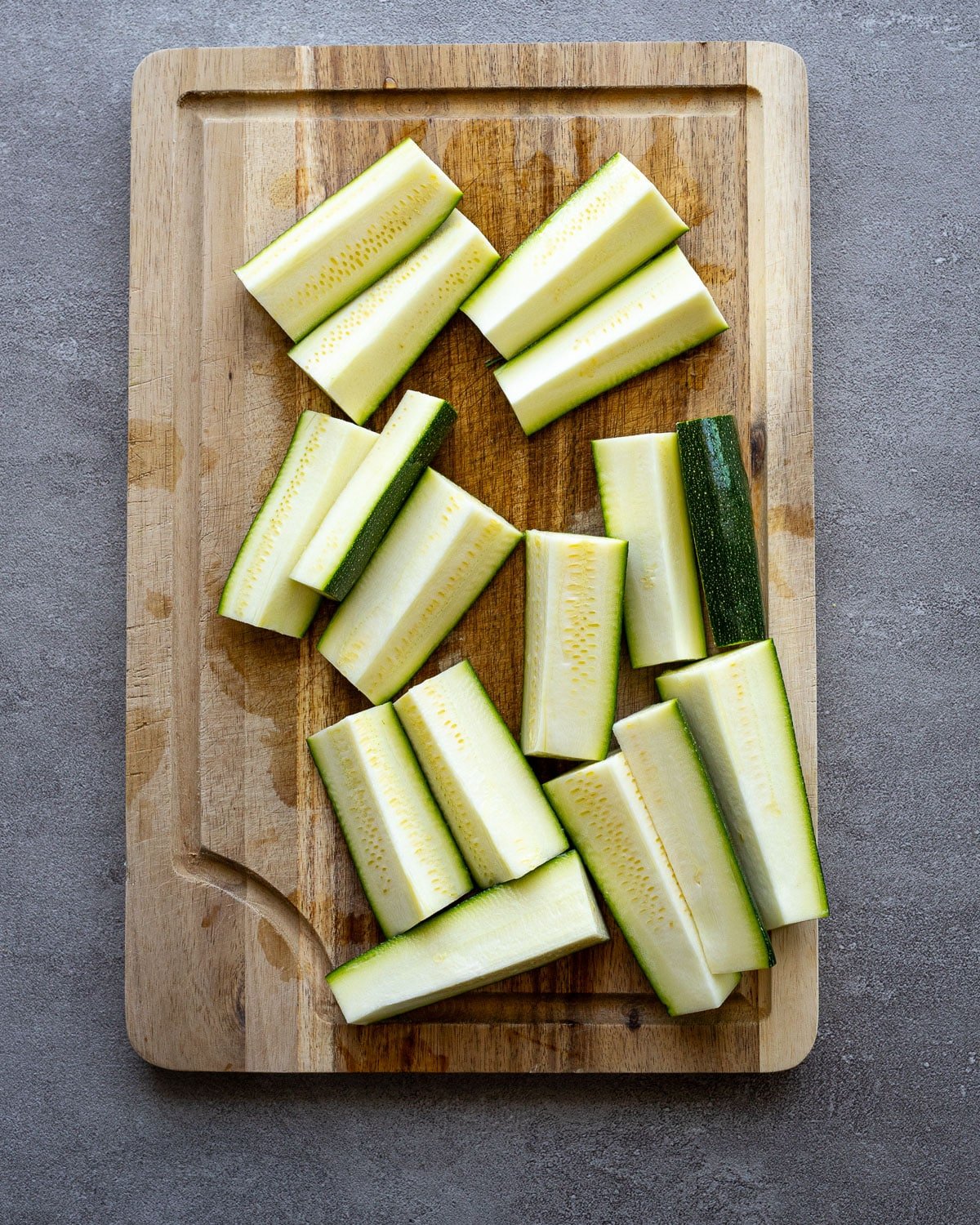 Fresh zucchini cut on a wooden cutting board.