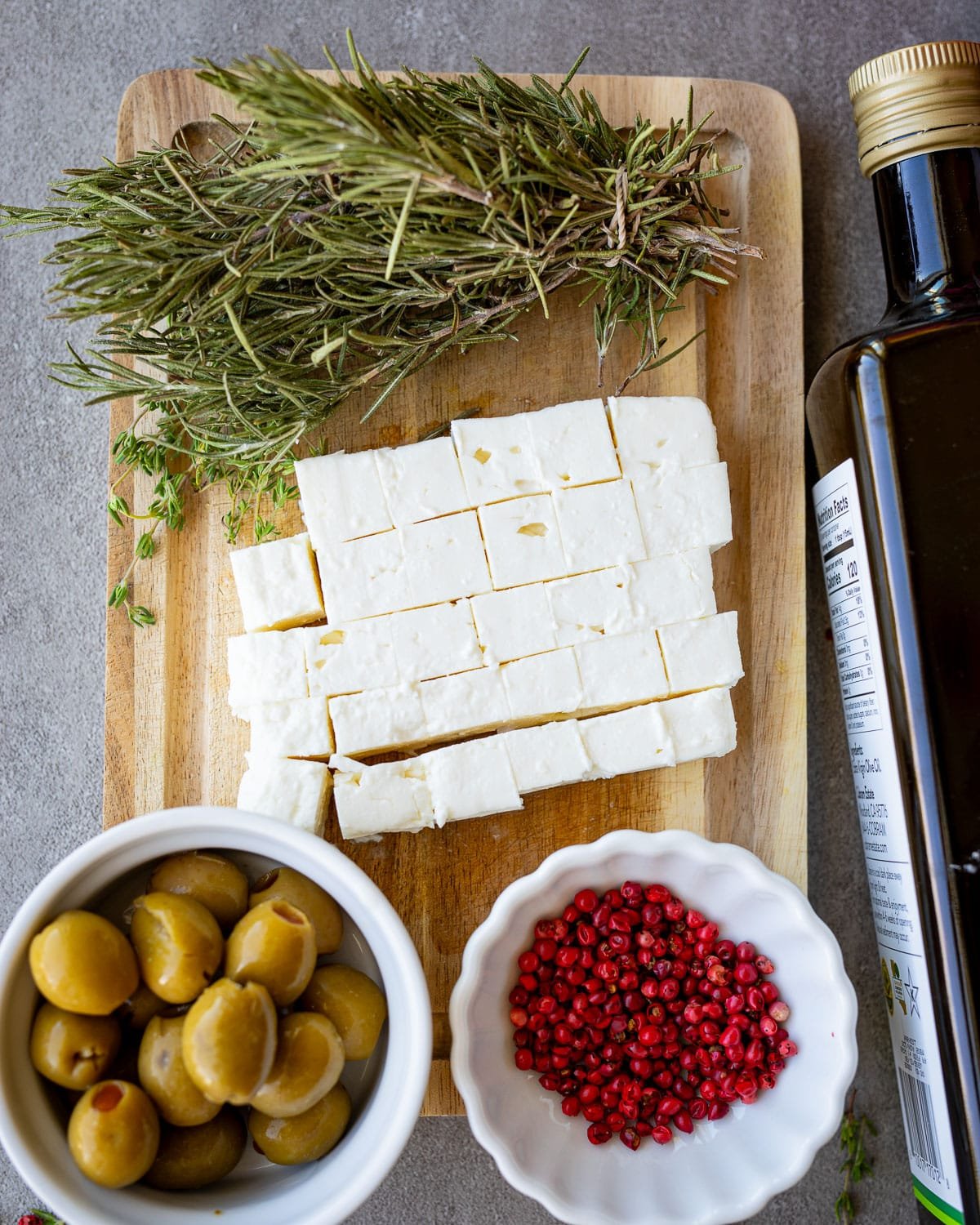 Ingredients for marinated feta on a wooden cutting board. 