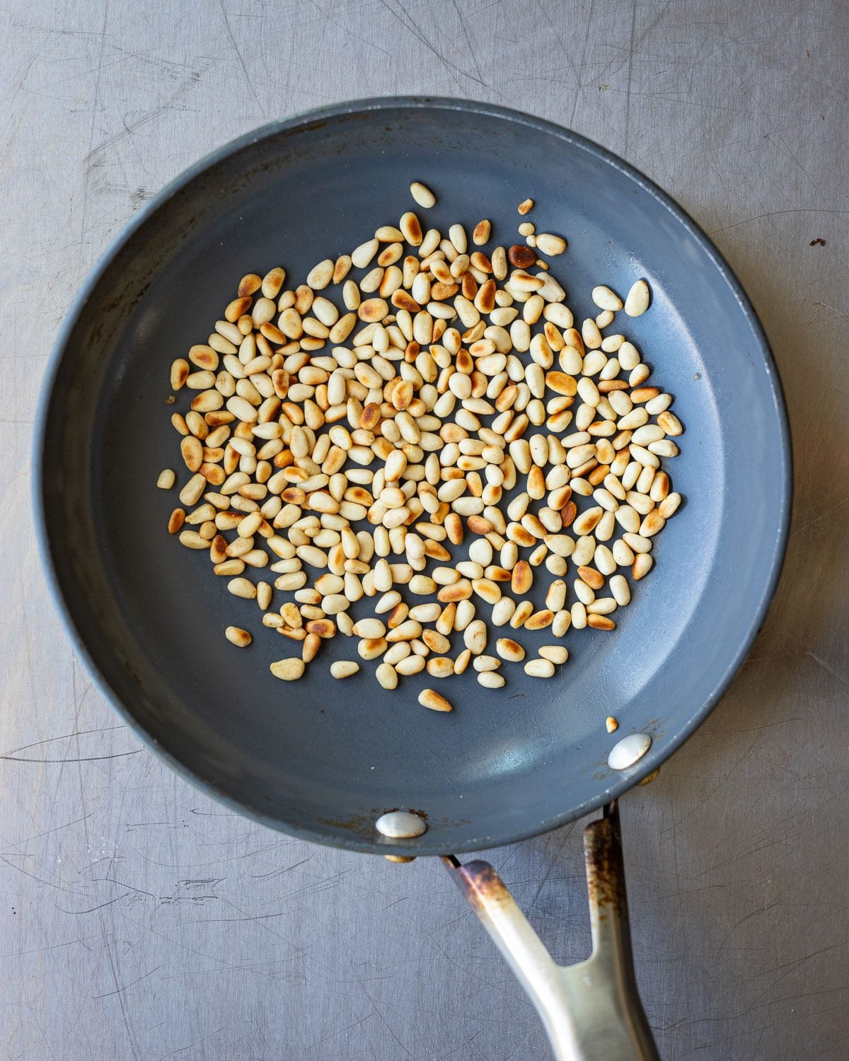 Toasted pine nuts in a small pan. 