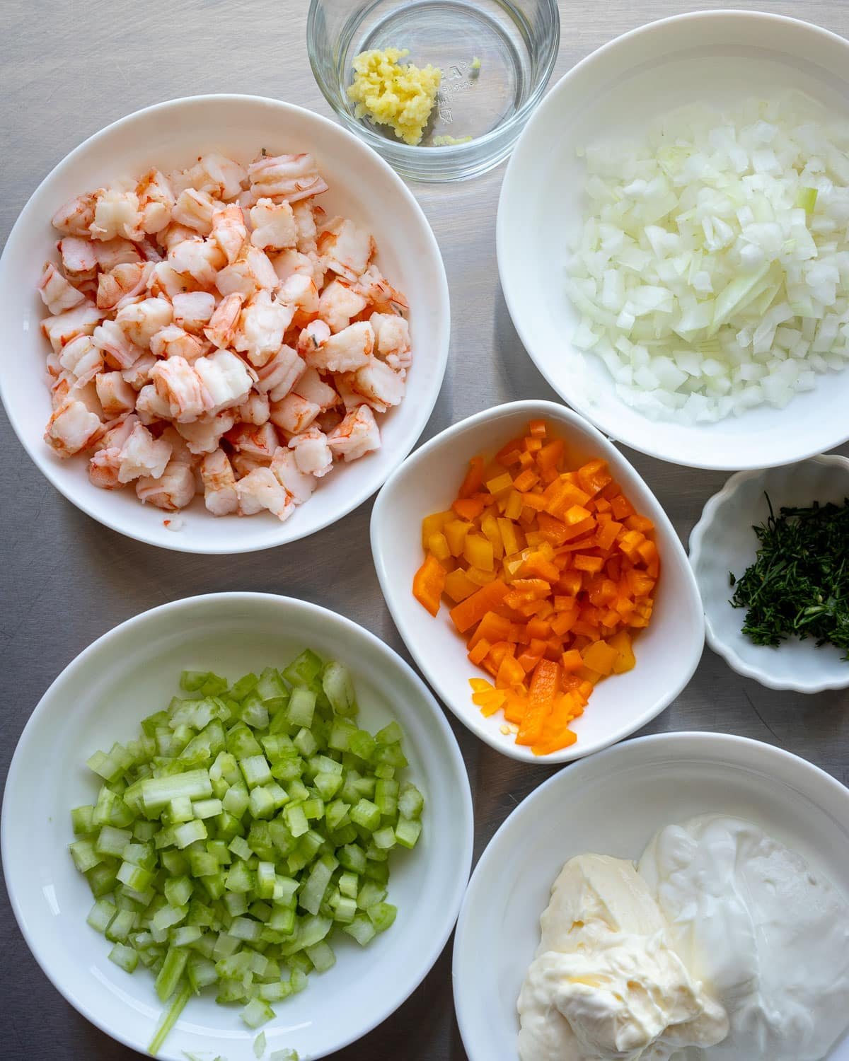 Ingredients for shrimp salad in small bowls.