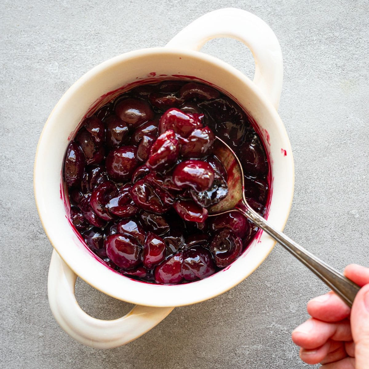 Roasted cherries in a white serving dish. 