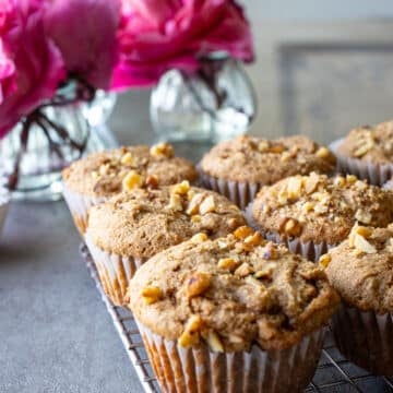 Sprouted wheat flour muffins on a cooling rack with flowers in the background.