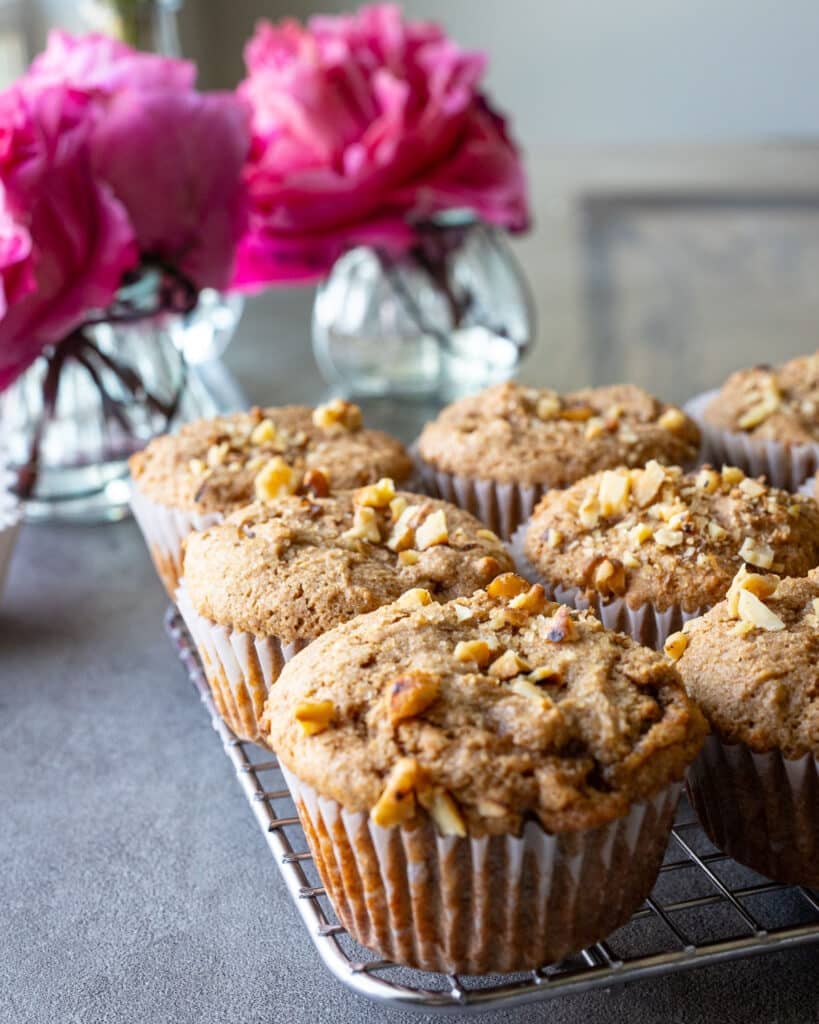 Sprouted wheat flour muffins on a cooling rack with flowers in the background. 