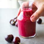 Woman holding a glass container of cherry vinaigrette.