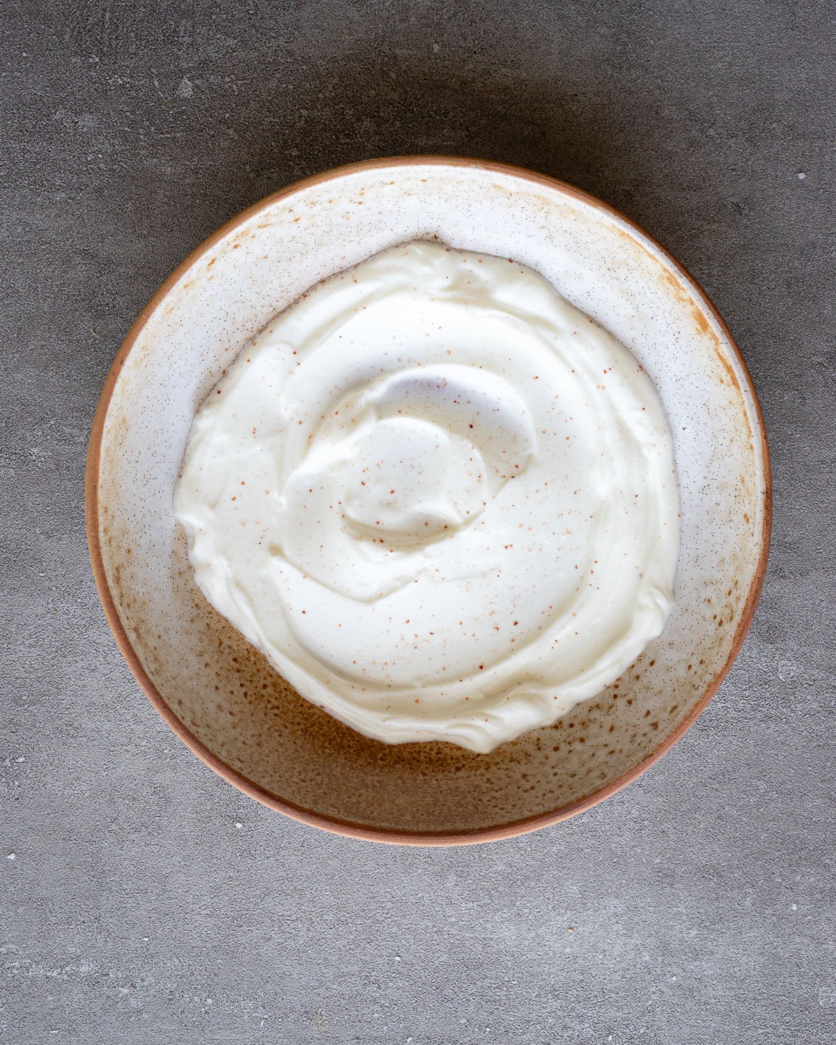 Greek yogurt in the bottom of a ceramic bowl.