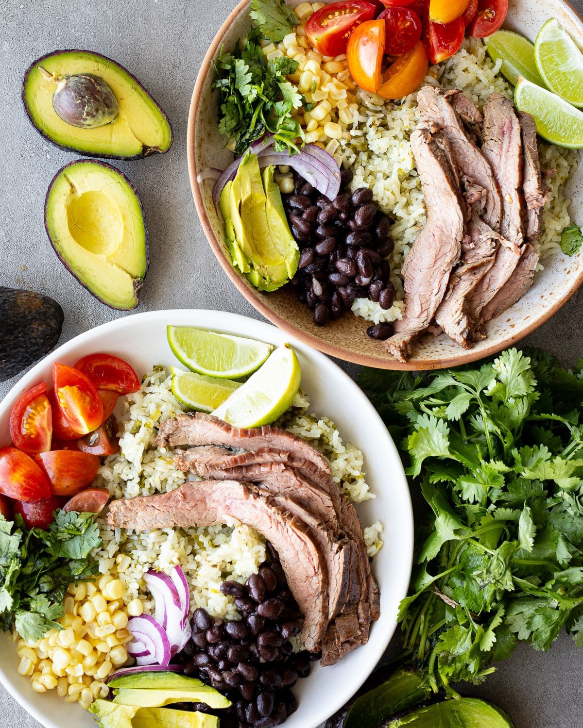 Carne asada buddha bowls in a ceramic bowl with ingredients on the side.