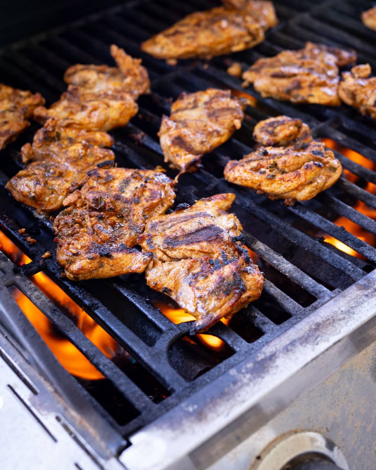 Chicken thighs on a gas grill cooking.