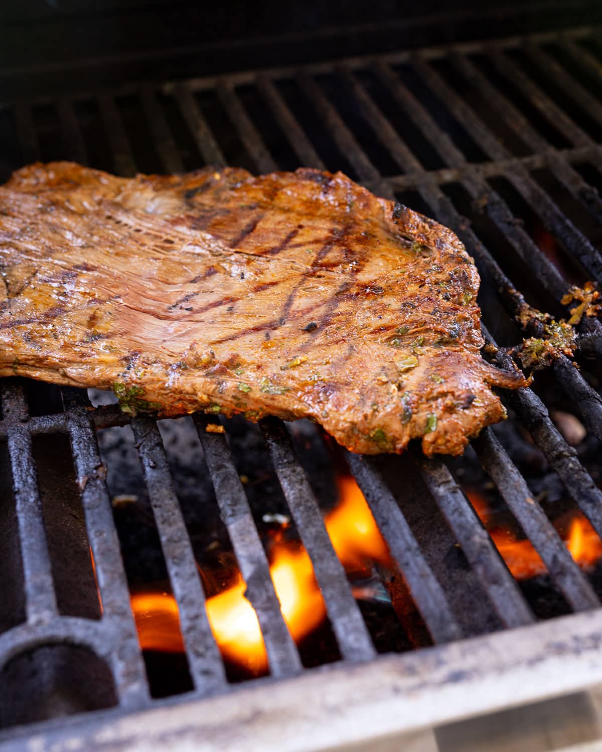 Flank steak grilling on a gas grill.