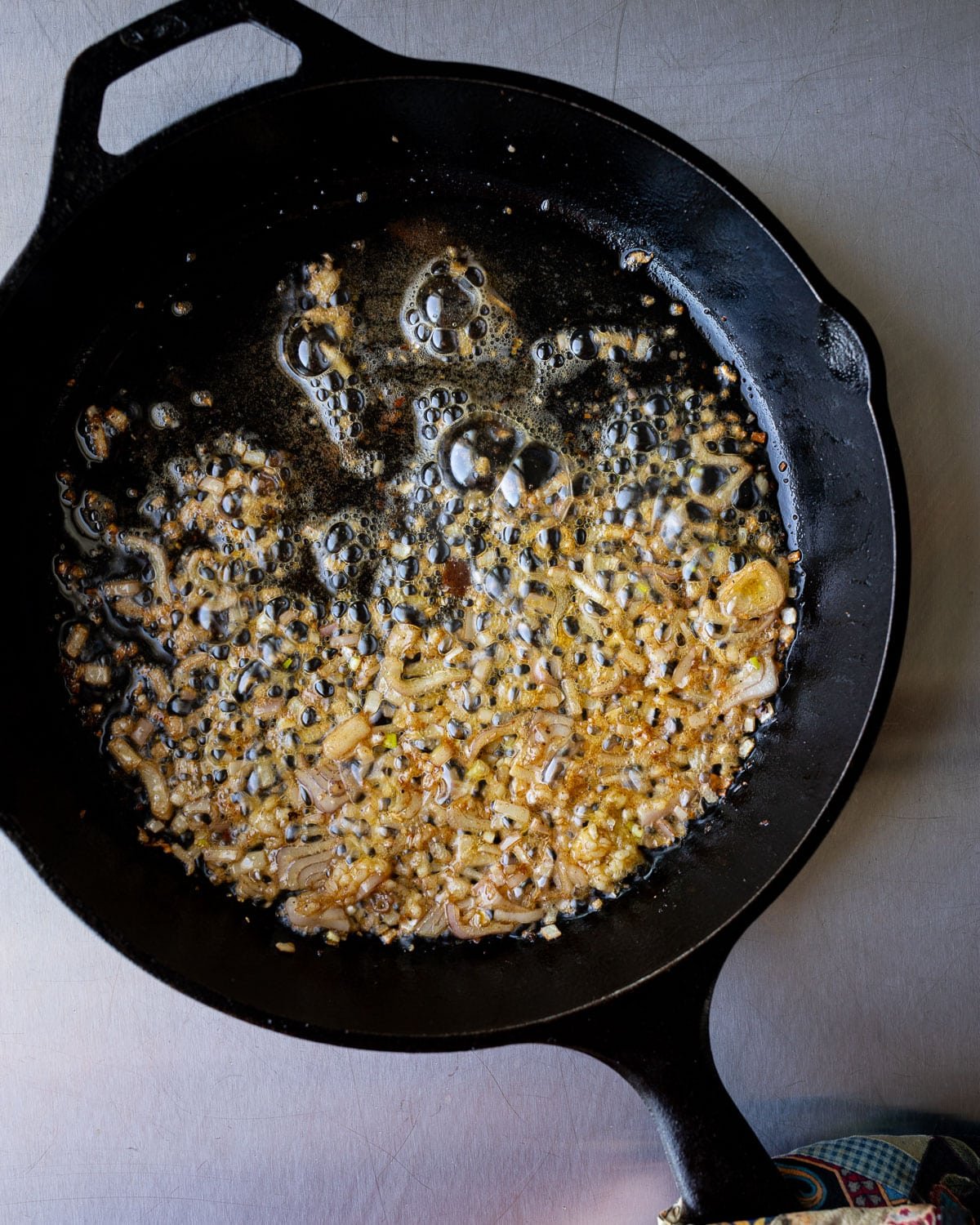 Shallots cooking in olive oil in a cast iron pan. 